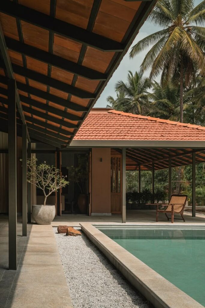 Modern luxury villa with sloped terracotta roof, poolside seating, and tropical palm trees – representing premium residential properties in South Delhi.